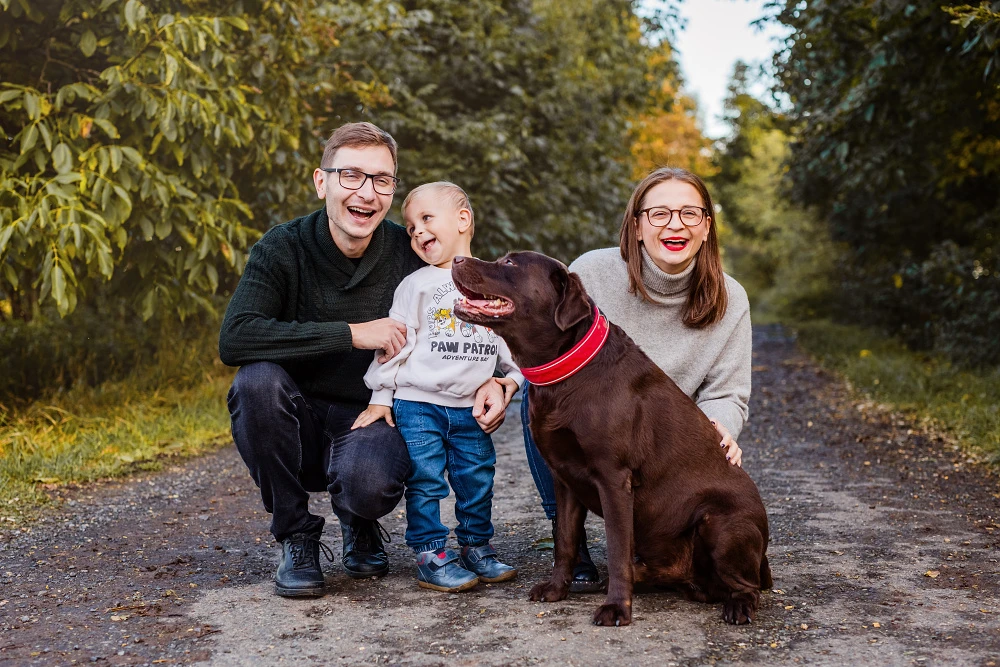 Rodina s čokoládovým labradorem na lesní cestě, podzim