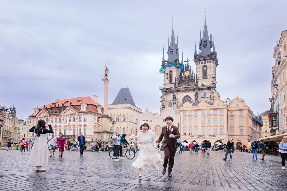 Novomanželé běží Staroměstským náměstím v Praze