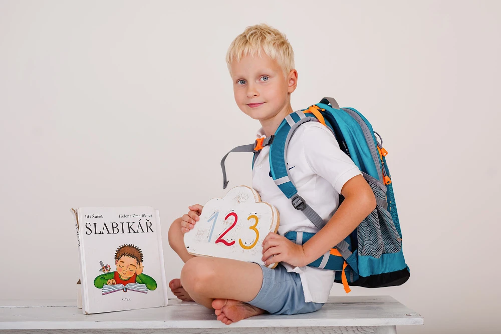 Prvňáček s aktovkou a slabikářem ve školní scéně